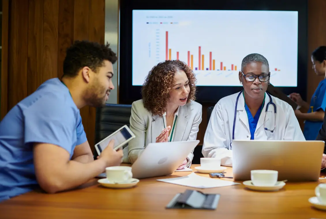 Medical professionals discussing data on laptops.