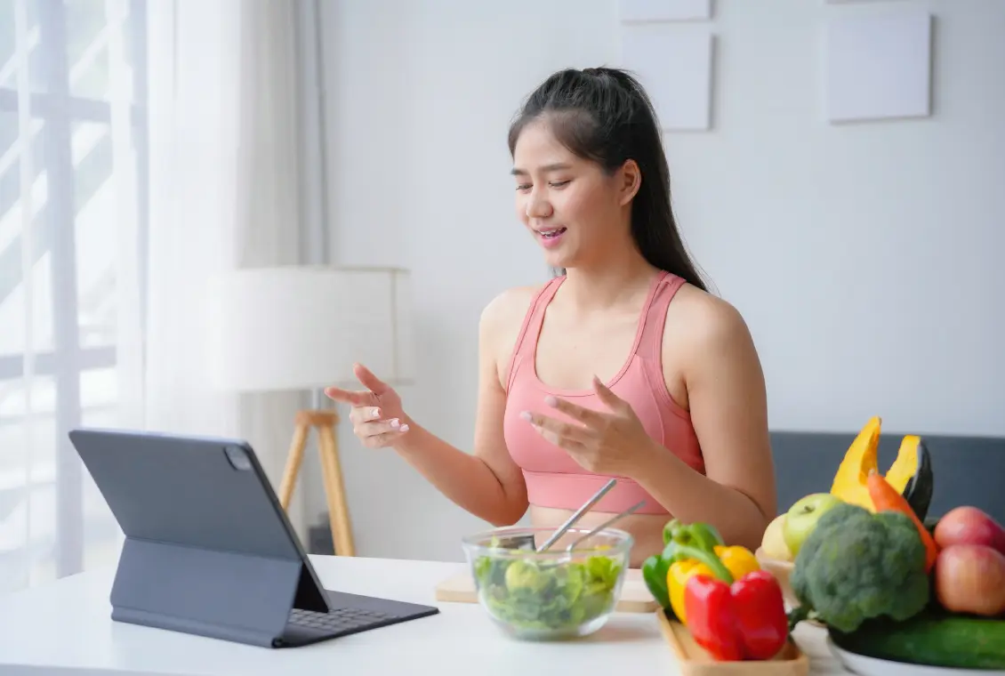 Woman video chatting with healthy food nearby.
