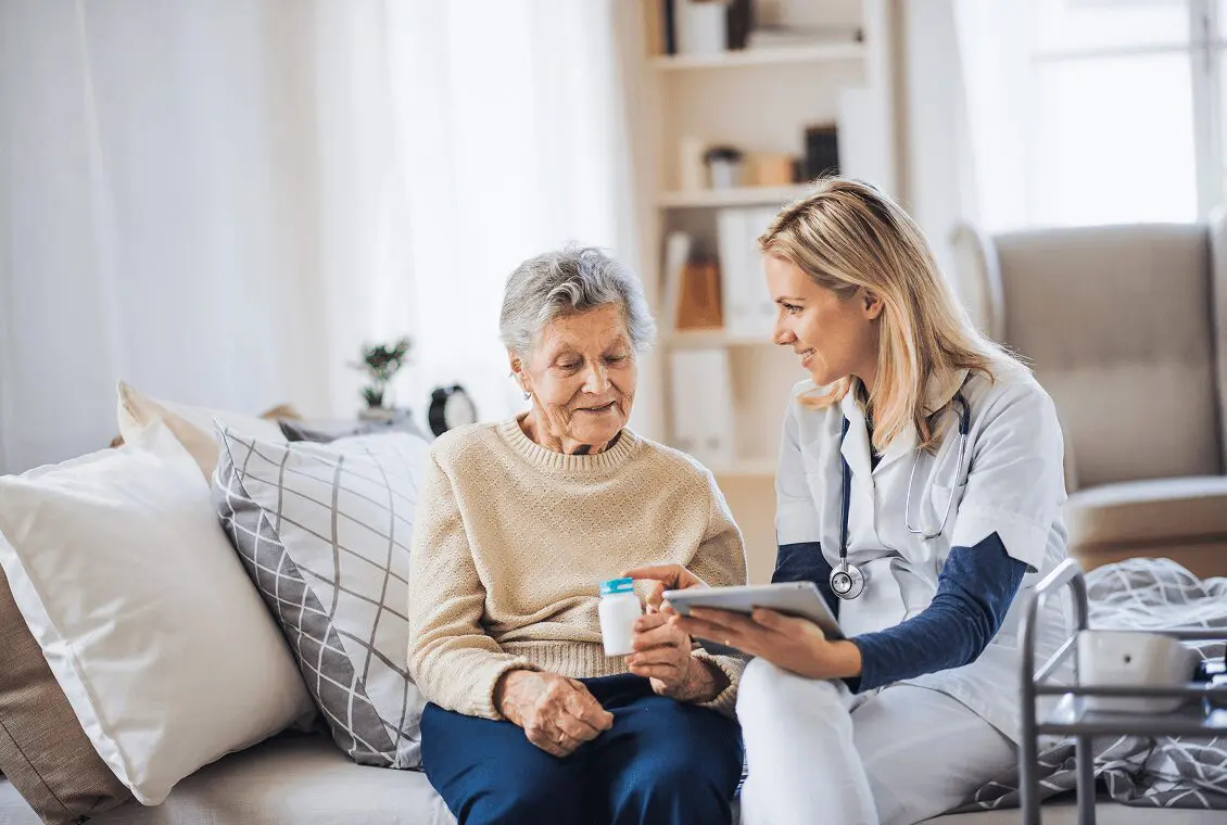 Nurse assisting elderly woman with medication.